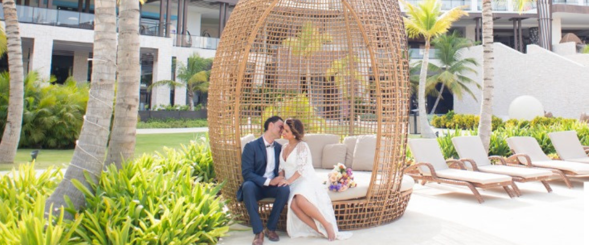 Destination wedding, bride and groom sitting on elegant beach chair, resort views