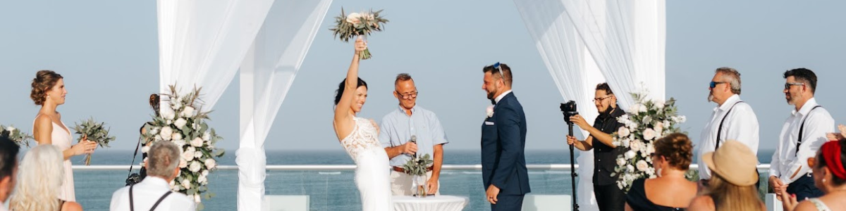 Bride with flowers in the air in celebration with groom and bridal party at the front of the ceremony at a destination wedding