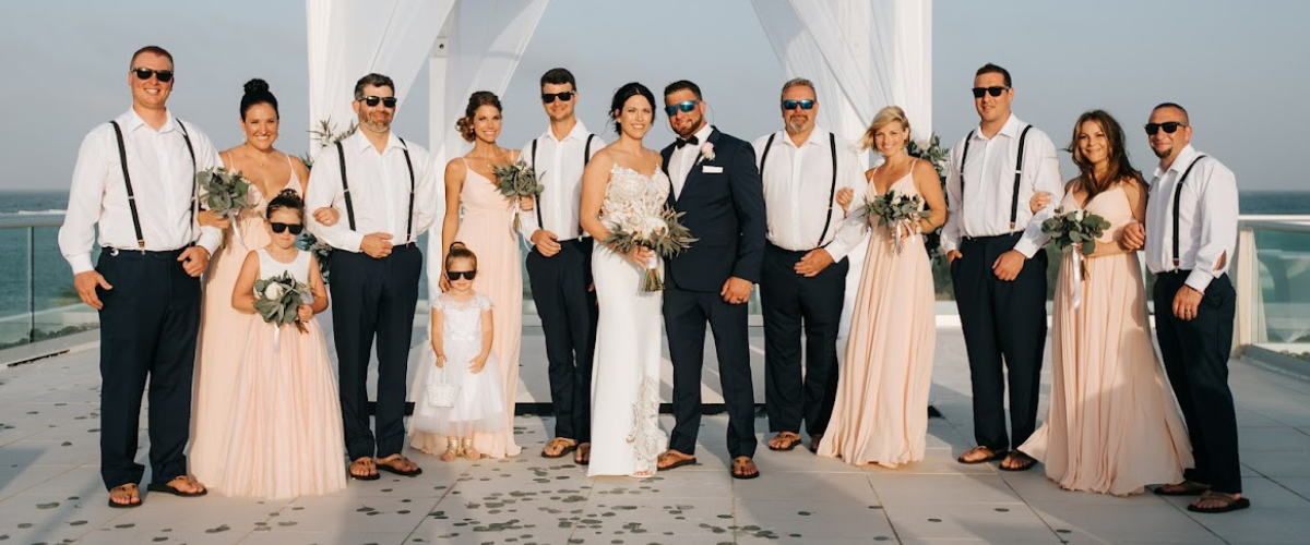 Bride and groom at destination wedding with their wedding party posing on the beach