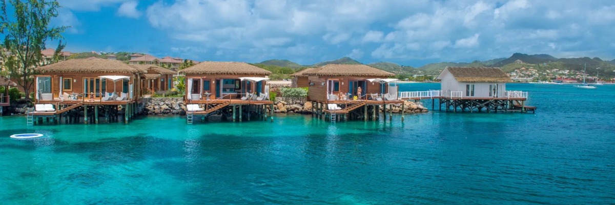 Four over the water bungalows with decks that have ladders going into the ocean with other bungalows in the background