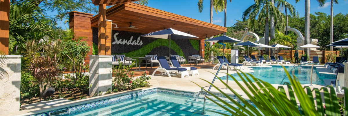 Sandals resort showing the pool area with a overhand to provide shade and other pool chairs around the pool with lots of green vegetation around 