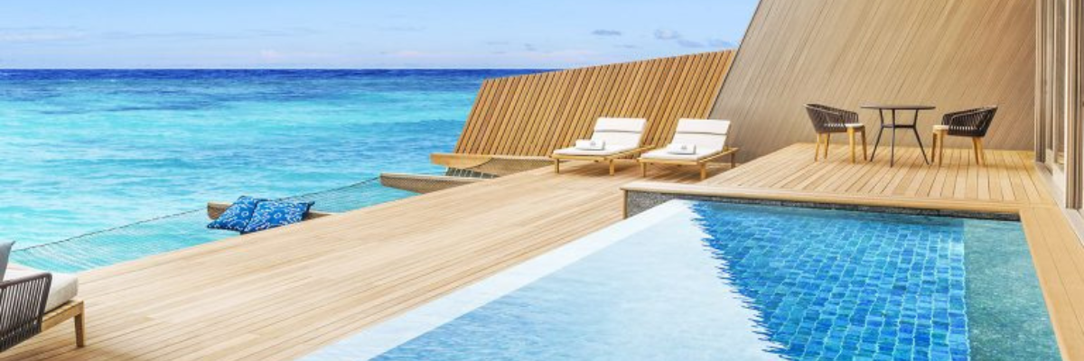 A balcony at an all inclusive resort in Aruba with a private plunge pool, lawn chairs, and hammocks over the ocean