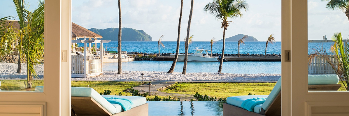 All inclusive resort in St. Vincent and Grenadine Islands showing a private balcony with a plunge pool with view of the ocean and mountains in the background