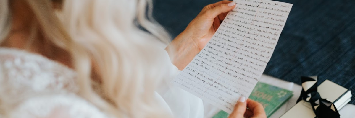 View behind the bride showing just her hair and her hands holding a letter from the groom